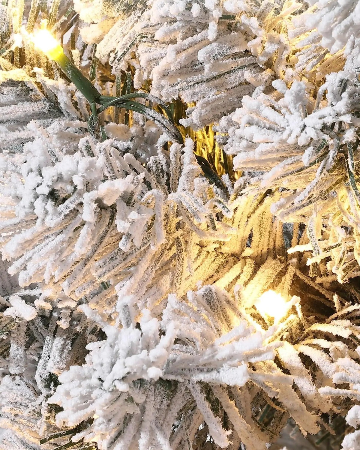 A close look at the pre-lit tree's snow flocked branch tips with their warm white lights on