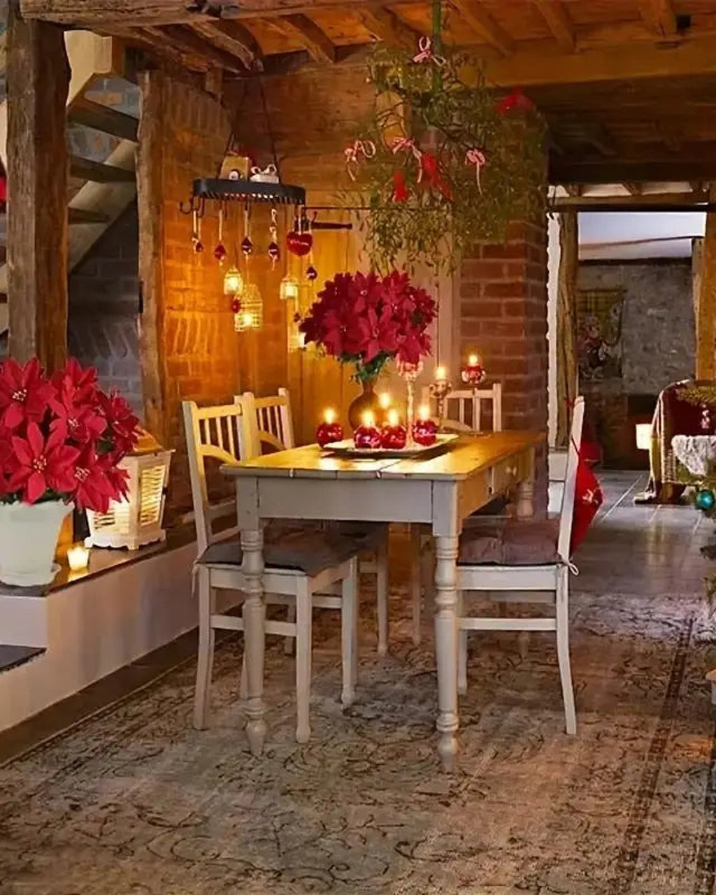 Red poinsettia bouquets in a dining room, one in a white pot by the window; pots not included
