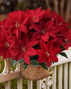 A red poinsettia bouquet in a woven basket hung on a white fence; basket not included