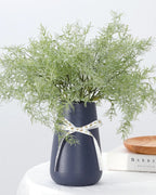 Artificial rosemary sprays in a navy vase tied with a ribbon; vase not included