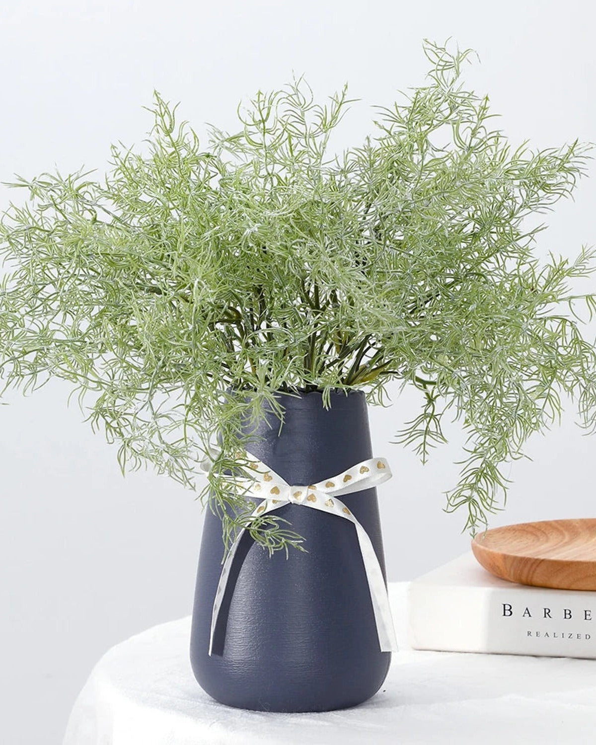 Artificial rosemary sprays in a navy vase tied with a ribbon; vase not included