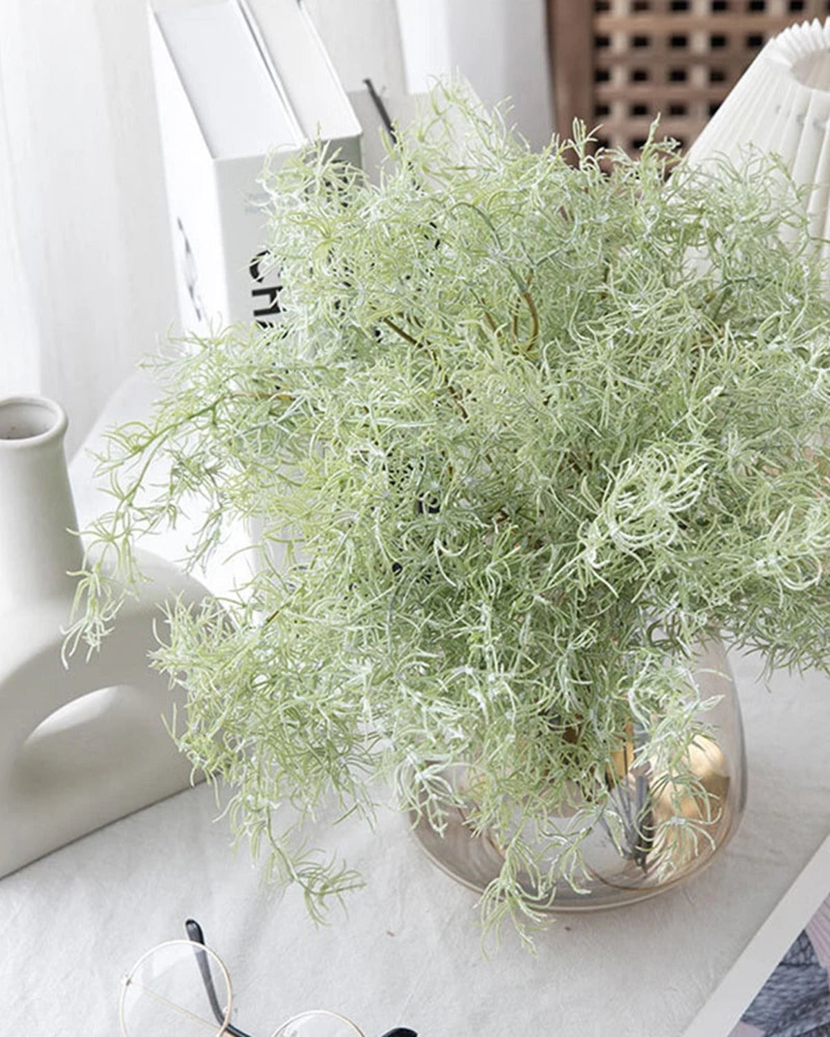 Artificial rosemary sprays in a glass bowl vase beside a lamp; vase not included
