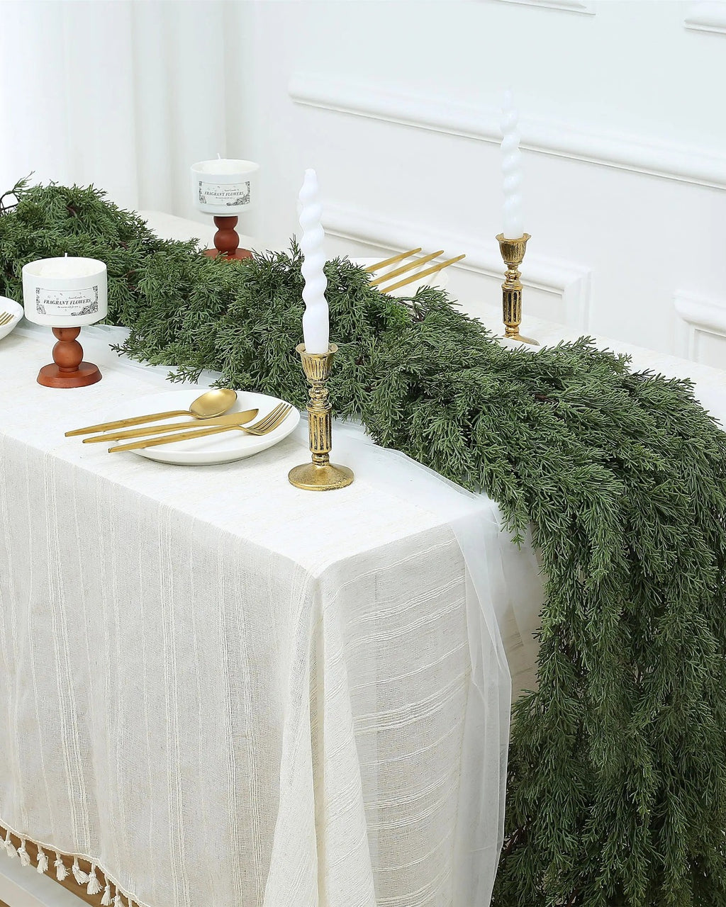 An artificial cedar garland running the length of a white dining table