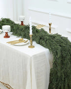 An artificial cedar garland running the length of a white dining table