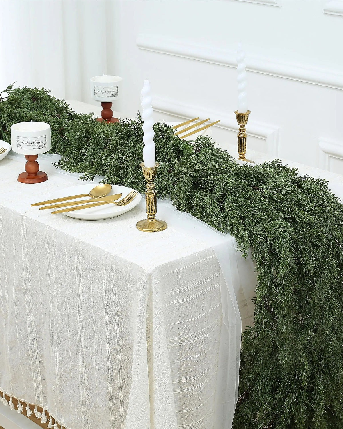 An artificial cedar garland running the length of a white dining table