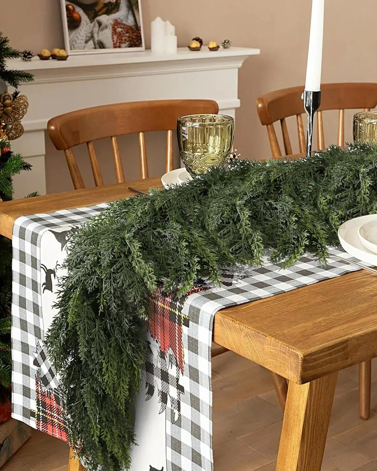 An artificial cypress garland laid down a dining table over a checked runner