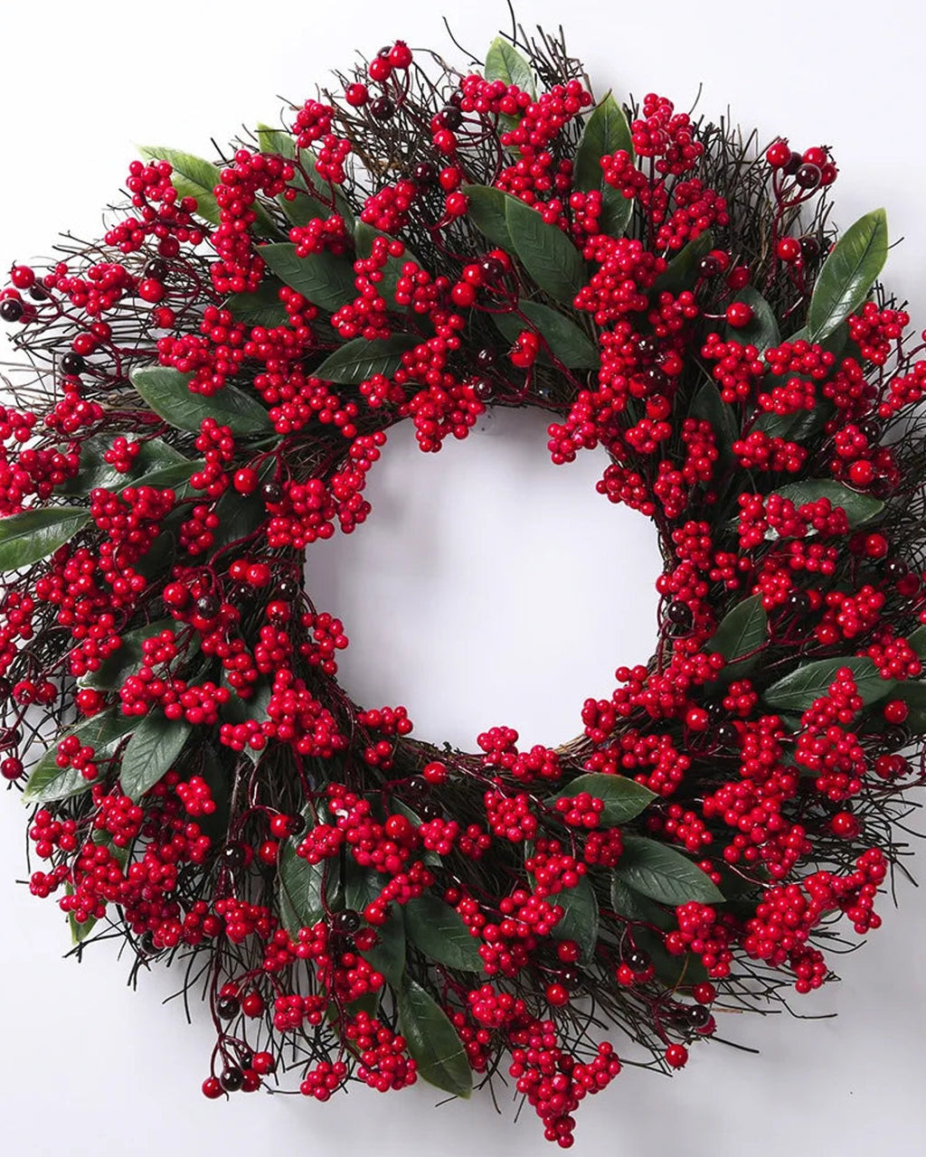 The berry and twig wreath on a plain white ground, red berries and long green leaves on a twig base
