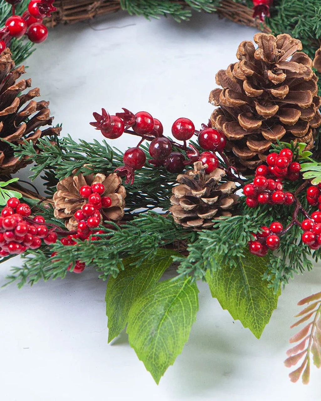 A close look at the cypress and pinecone wreath, pinecones, red berries and fern on a twig base