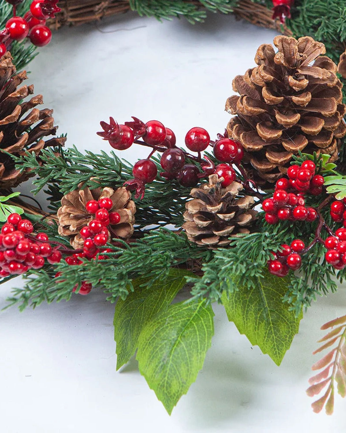 A close look at the cypress and pinecone wreath, pinecones, red berries and fern on a twig base