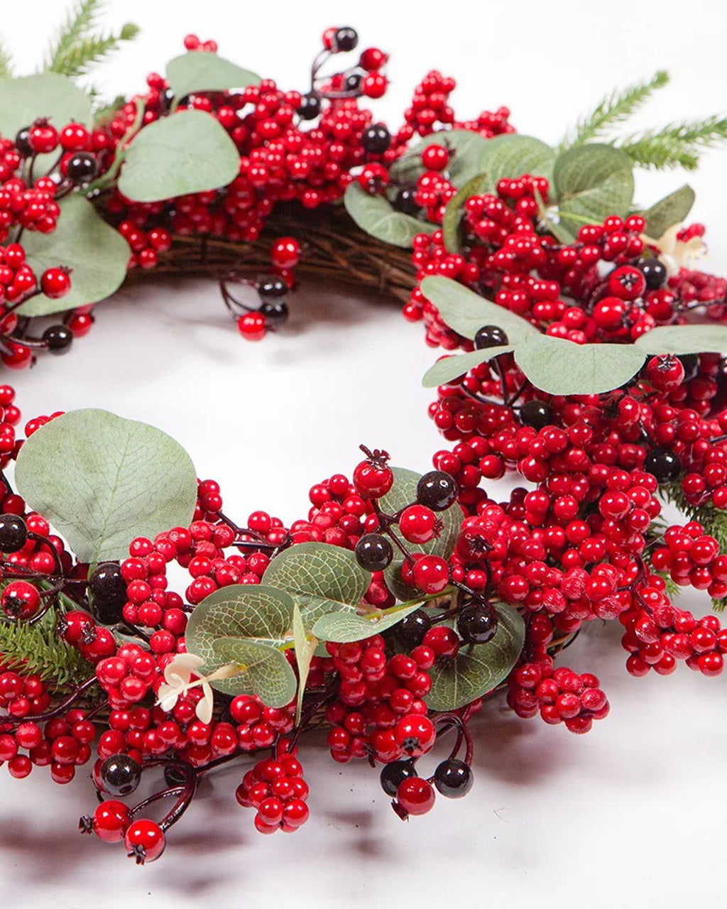 The berry and eucalyptus wreath from a low angle, showing its twig base