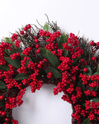 A close look at the berry and twig wreath's red berries and long green leaves on the twig ring