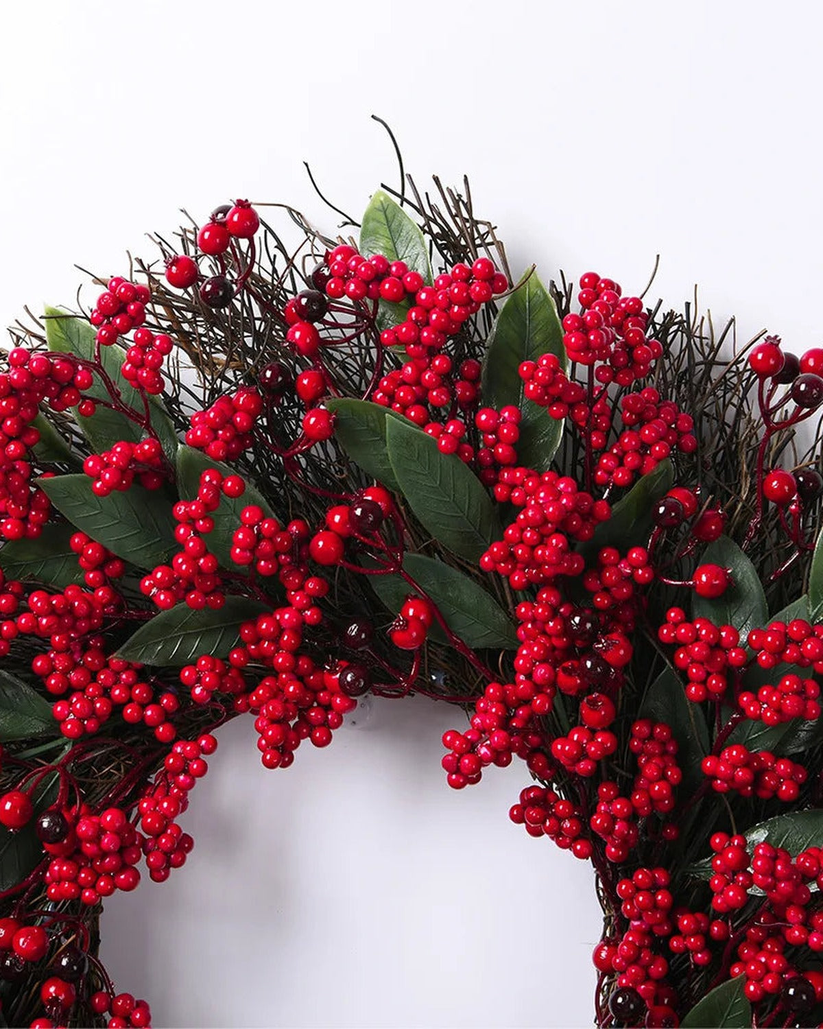 A close look at the berry and twig wreath's red berries and long green leaves on the twig ring