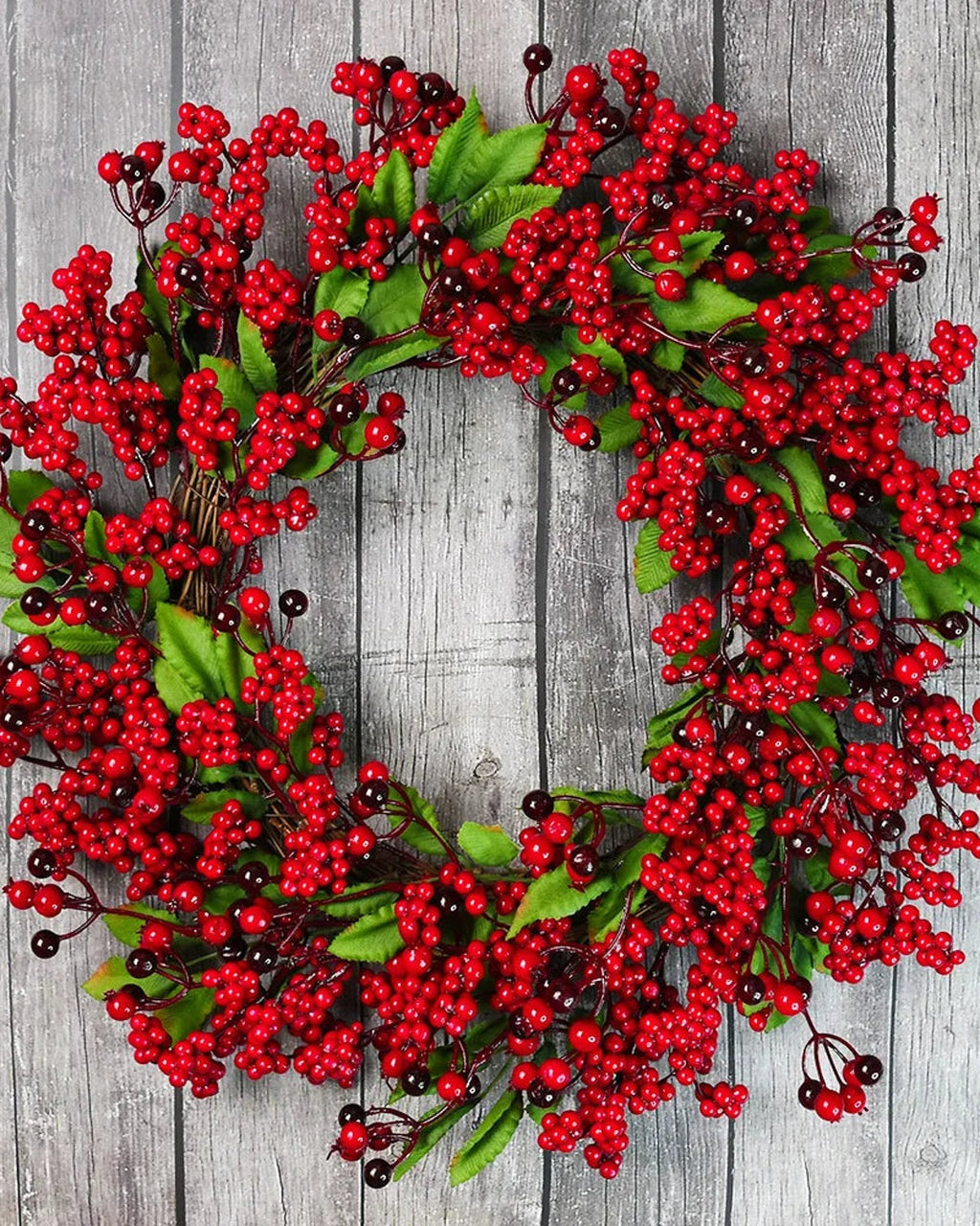 The berry and leaf wreath on a gray wooden wall