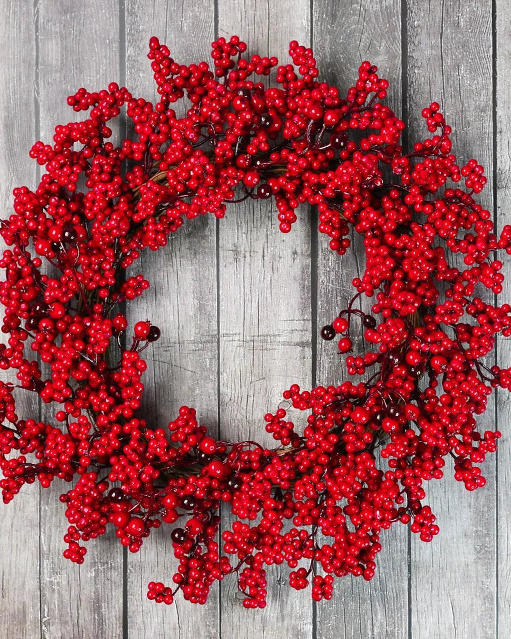 The red berry wreath on a gray wooden wall