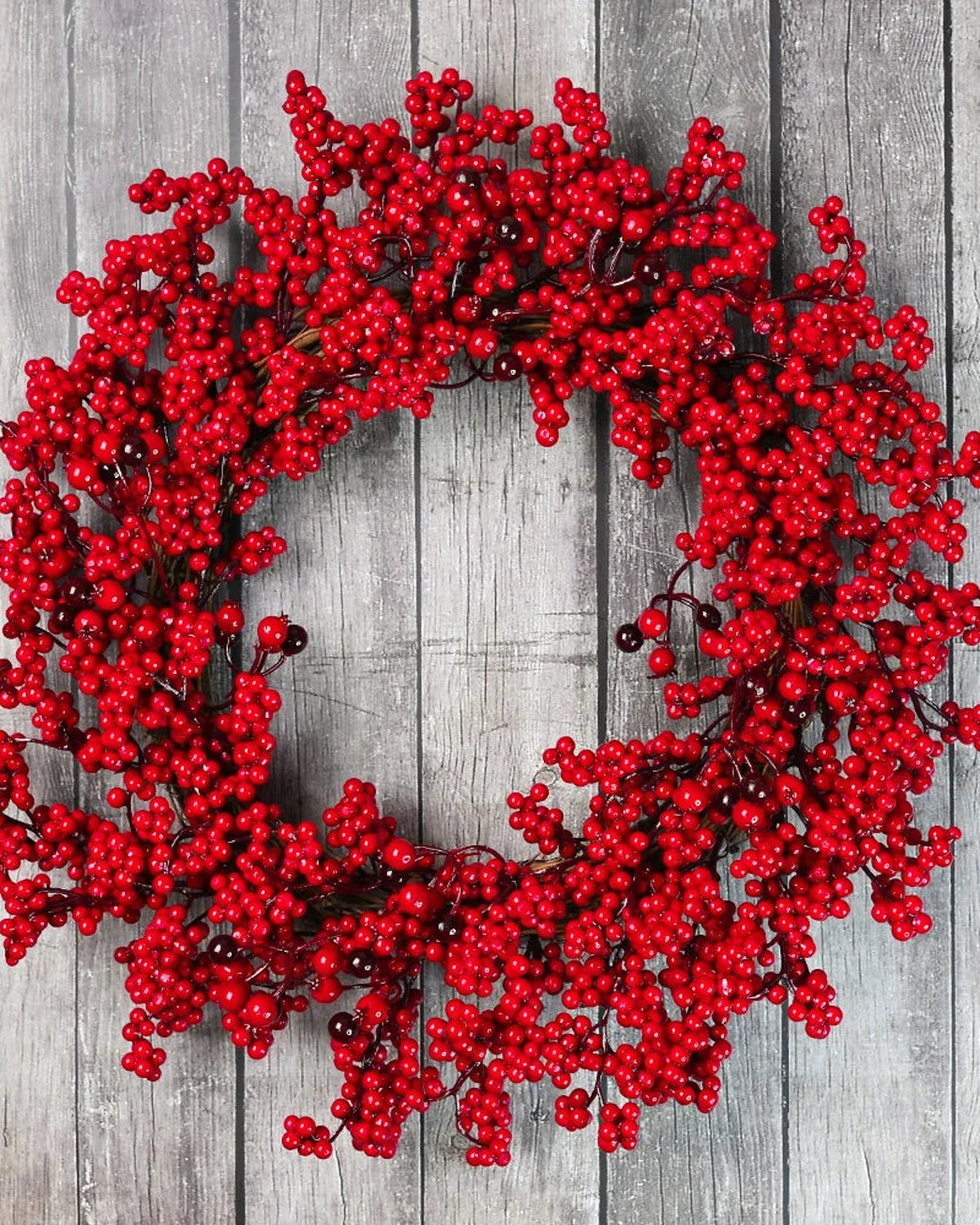 The red berry wreath on a gray wooden wall