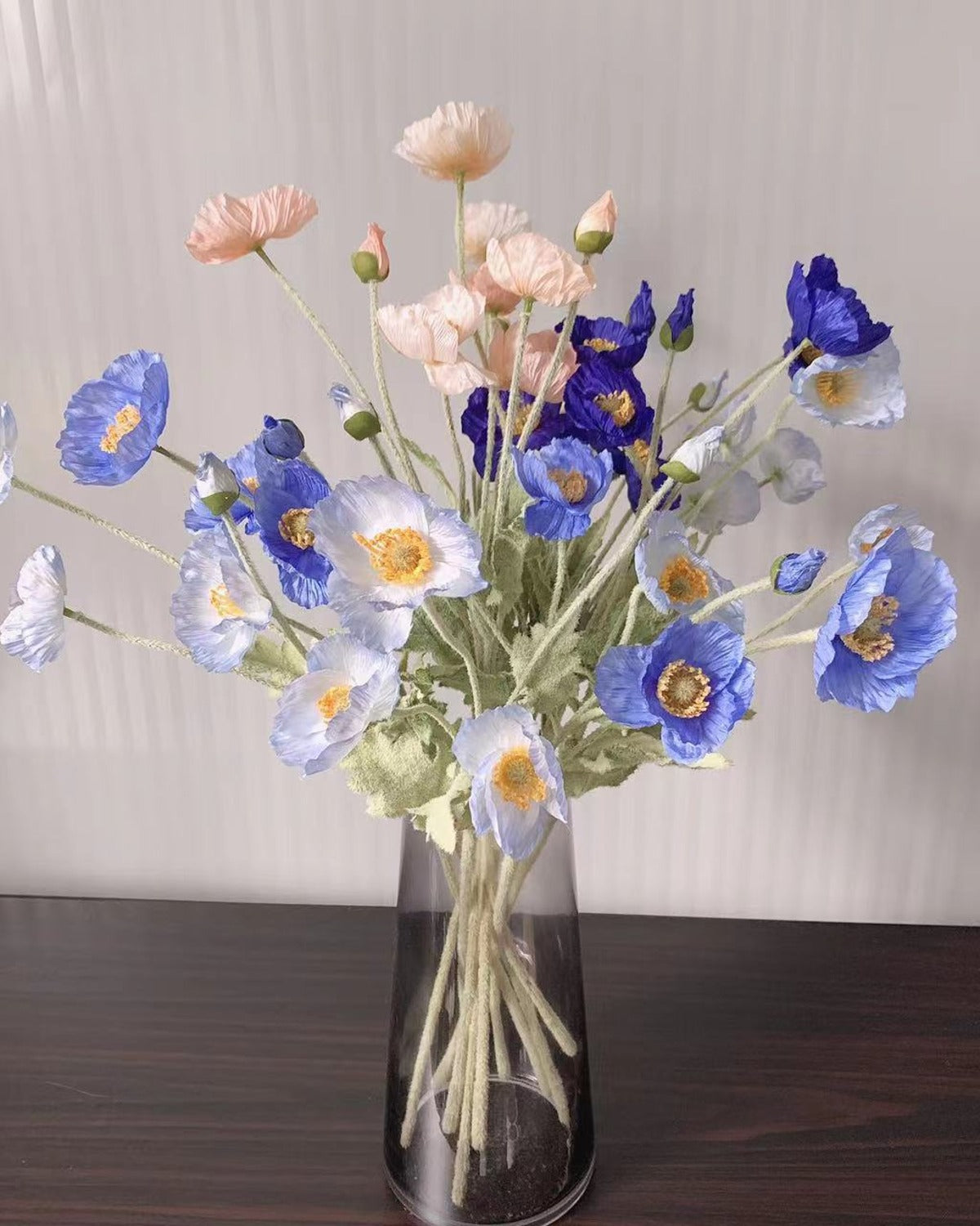 Blue and white poppies arranged together in a glass vase