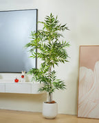 The bamboo branch in a white pot beside a low media unit and a leaning mirror (pot not included)