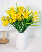 Daffodils in a white vase beside a pleated lamp