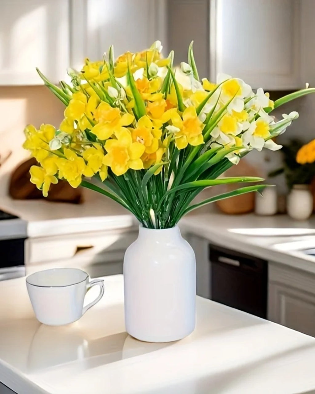 Daffodils in a white jug on a kitchen counter beside a teacup