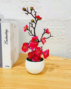 The rose red blossom bonsai on a wooden surface beside a stack of books