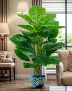 The elephant ear plant in a living room beside a lamp and an armchair (pot not included)