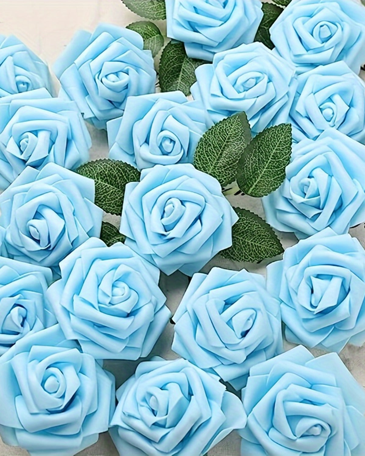 Sky blue foam rose heads with a leaf spray, seen close