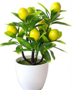The artificial lemon bonsai tree in its white pot on a plain white background.