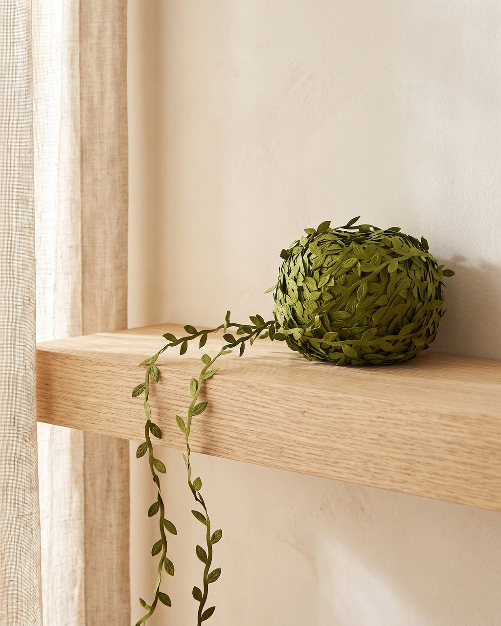 Artificial leaf trim vine draped along an oak shelf and trailing down