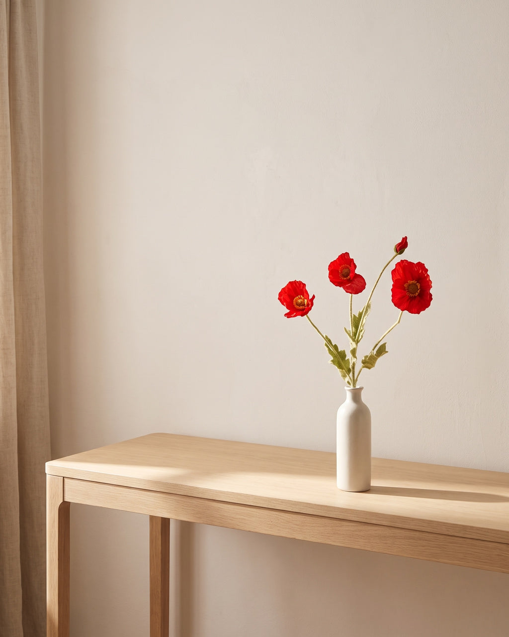 The same poppies on a bare console table in a sunlit room
