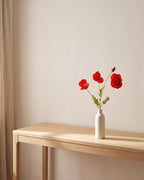 The same poppies on a bare console table in a sunlit room