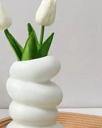 A spiral bud vase holding tulips on a wooden tray; tulips and tray not included