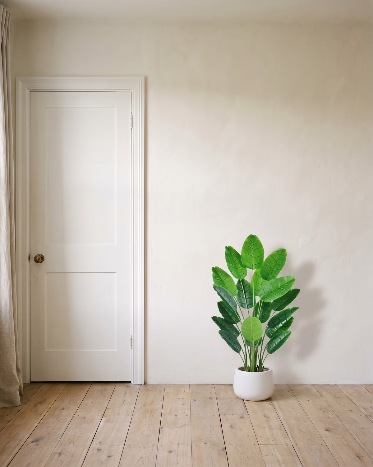 The 42 in artificial bird of paradise with eighteen leaves, in a plain white pot beside an 80 in door to show its height; pot not included