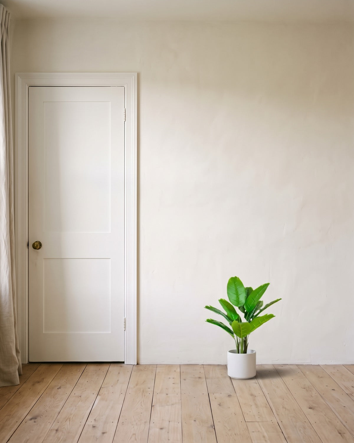 The 26 in artificial bird of paradise with twelve leaves, in a plain white pot beside an 80 in door to show its height; pot not included