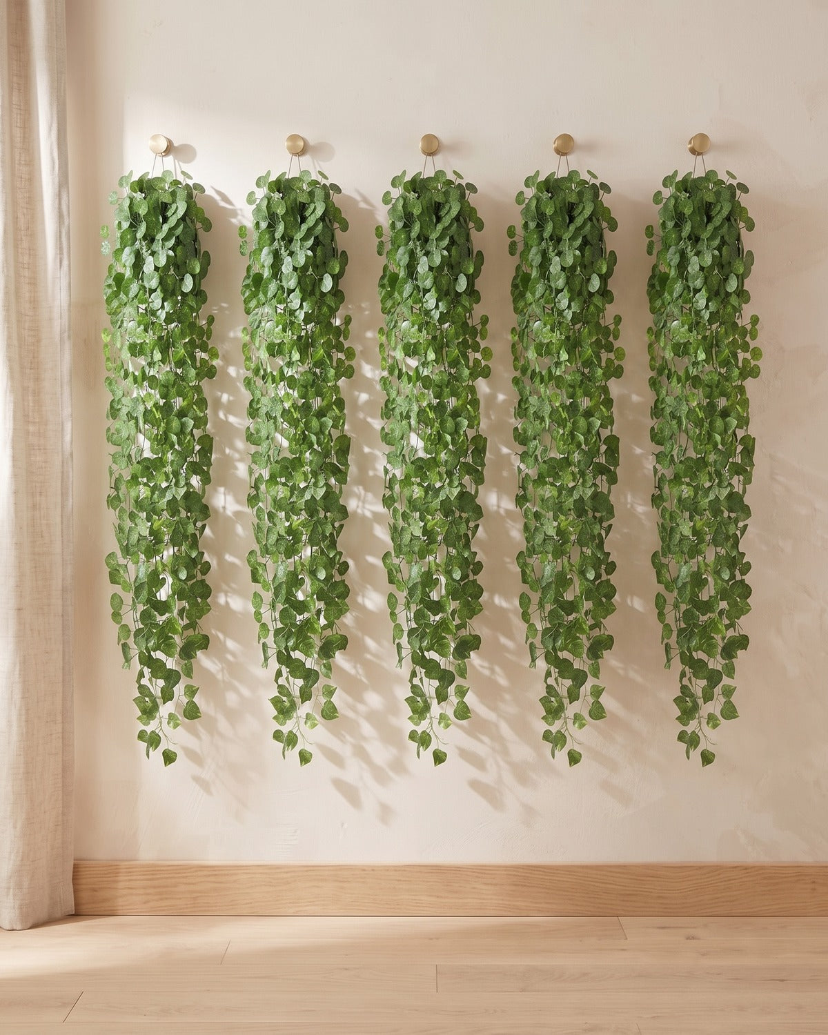 Five strands of the rounded leaf artificial ivy garland, 6.5 ft each, hanging side by side from five hooks on a plain wall: the 33 ft option
