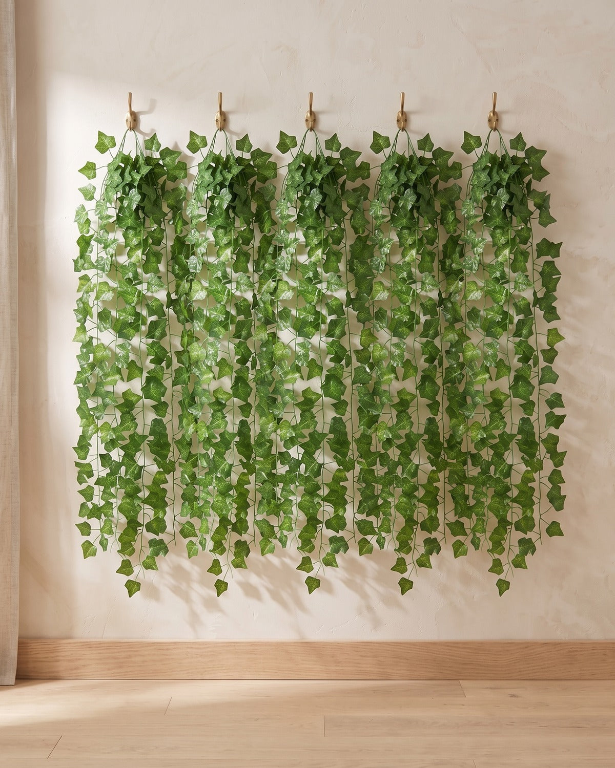 Five strands of the classic ivy leaf artificial ivy garland, 6.5 ft each, hanging side by side from five hooks on a plain wall: the 33 ft option