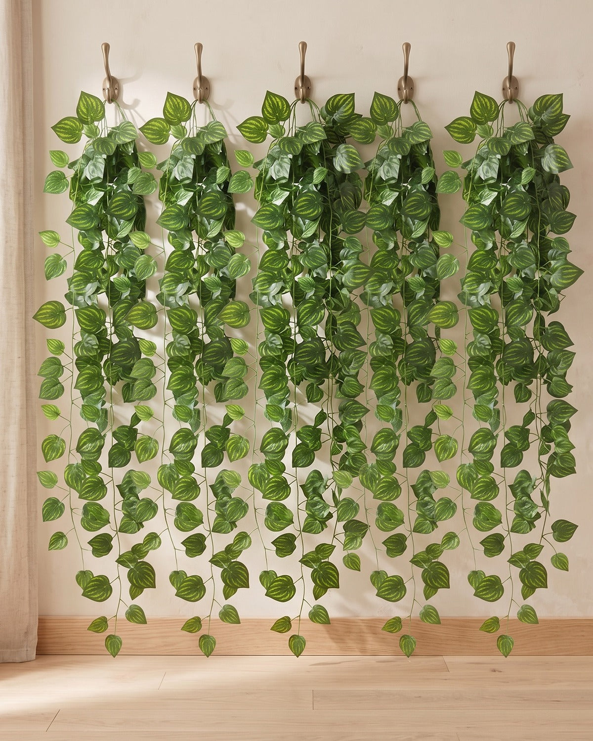 Five strands of the marbled leaf artificial ivy garland, 6.5 ft each, hanging side by side from five hooks on a plain wall: the 33 ft option
