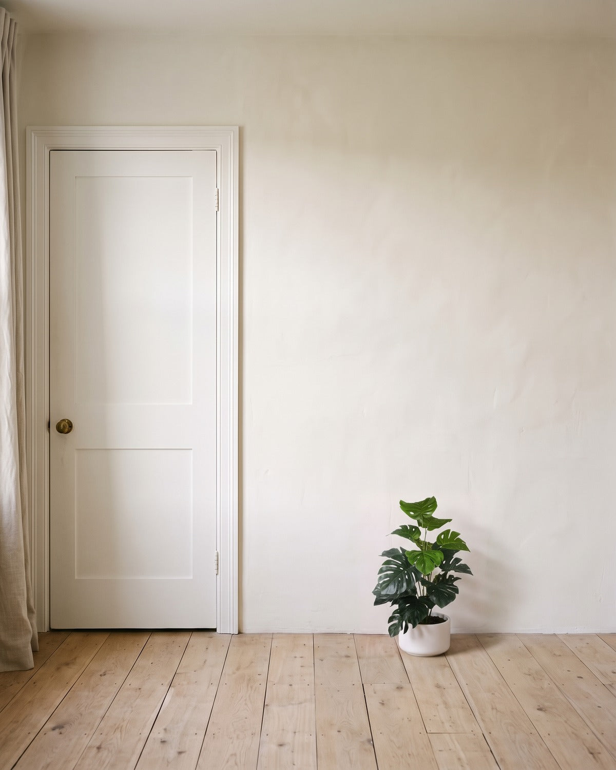 The 23.6 in artificial monstera plant with twelve leaves, in a plain white pot beside an 80 in door to show its height; pot not included