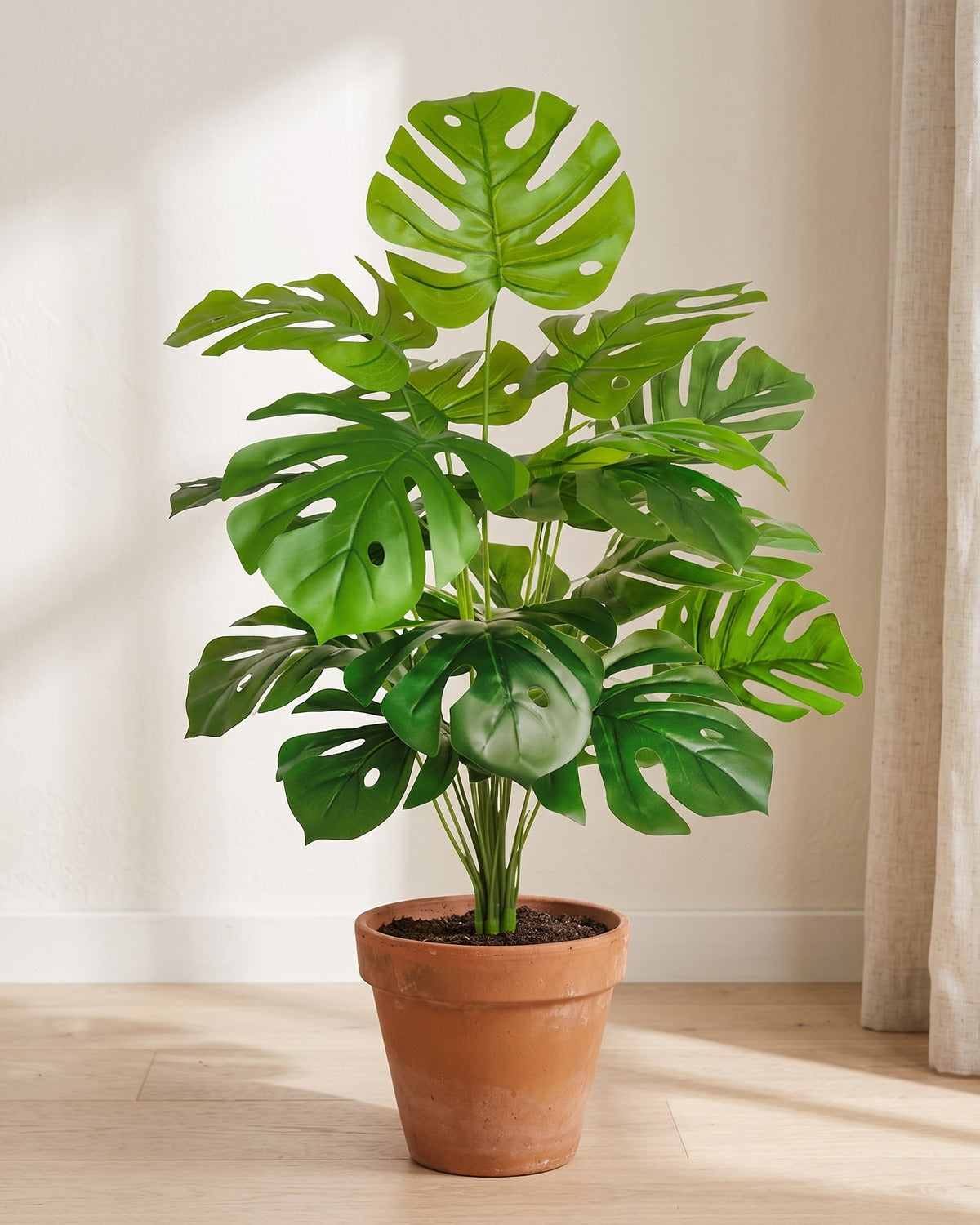 Pale green split leaf artificial leaf bush, 29.5 in with eighteen leaves, in a plain terracotta pot on pale oak floorboards; pot not included