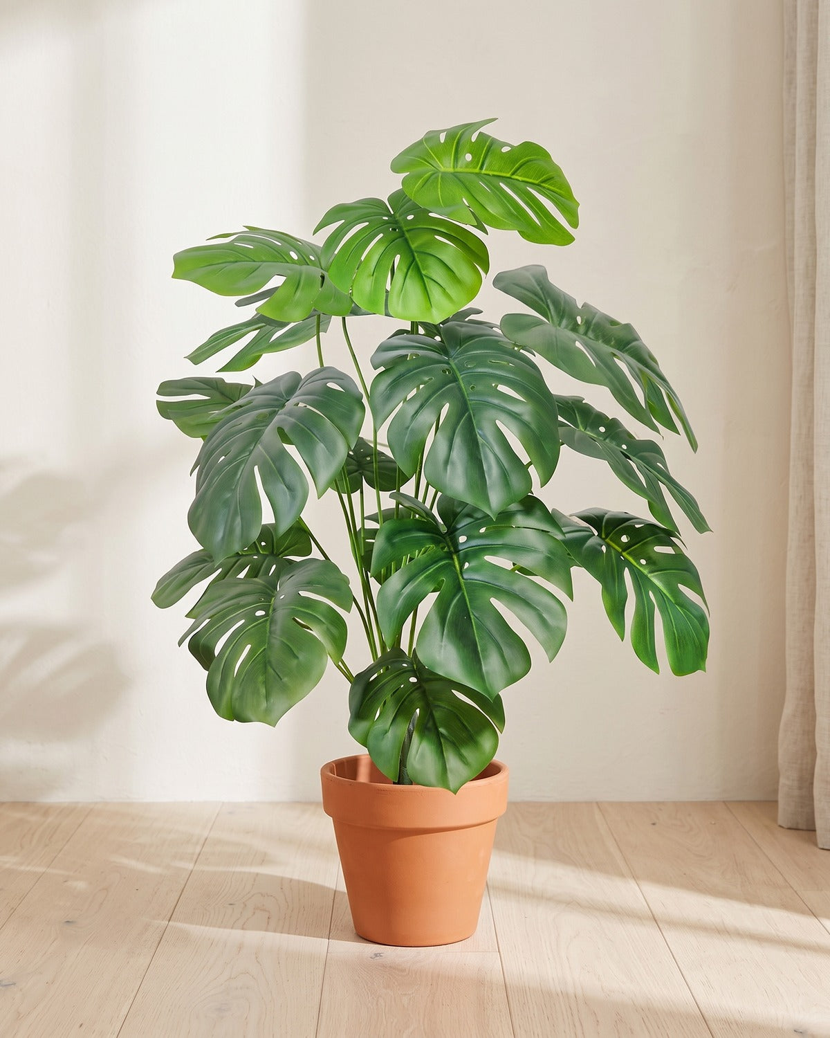 Deep green split leaf artificial leaf bush, 40.6 in with eighteen leaves, in a plain terracotta pot on pale oak floorboards; pot not included
