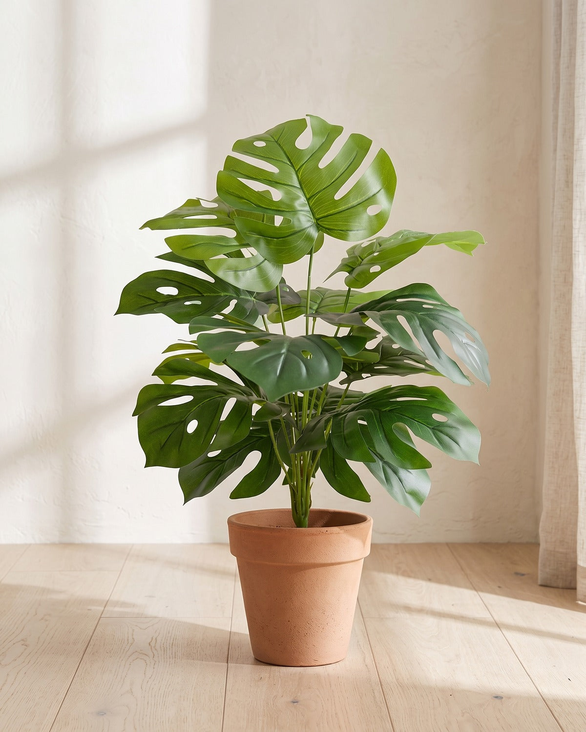 Mid green split leaf artificial leaf bush, 23.6 in with twelve leaves, in a plain terracotta pot on pale oak floorboards; pot not included