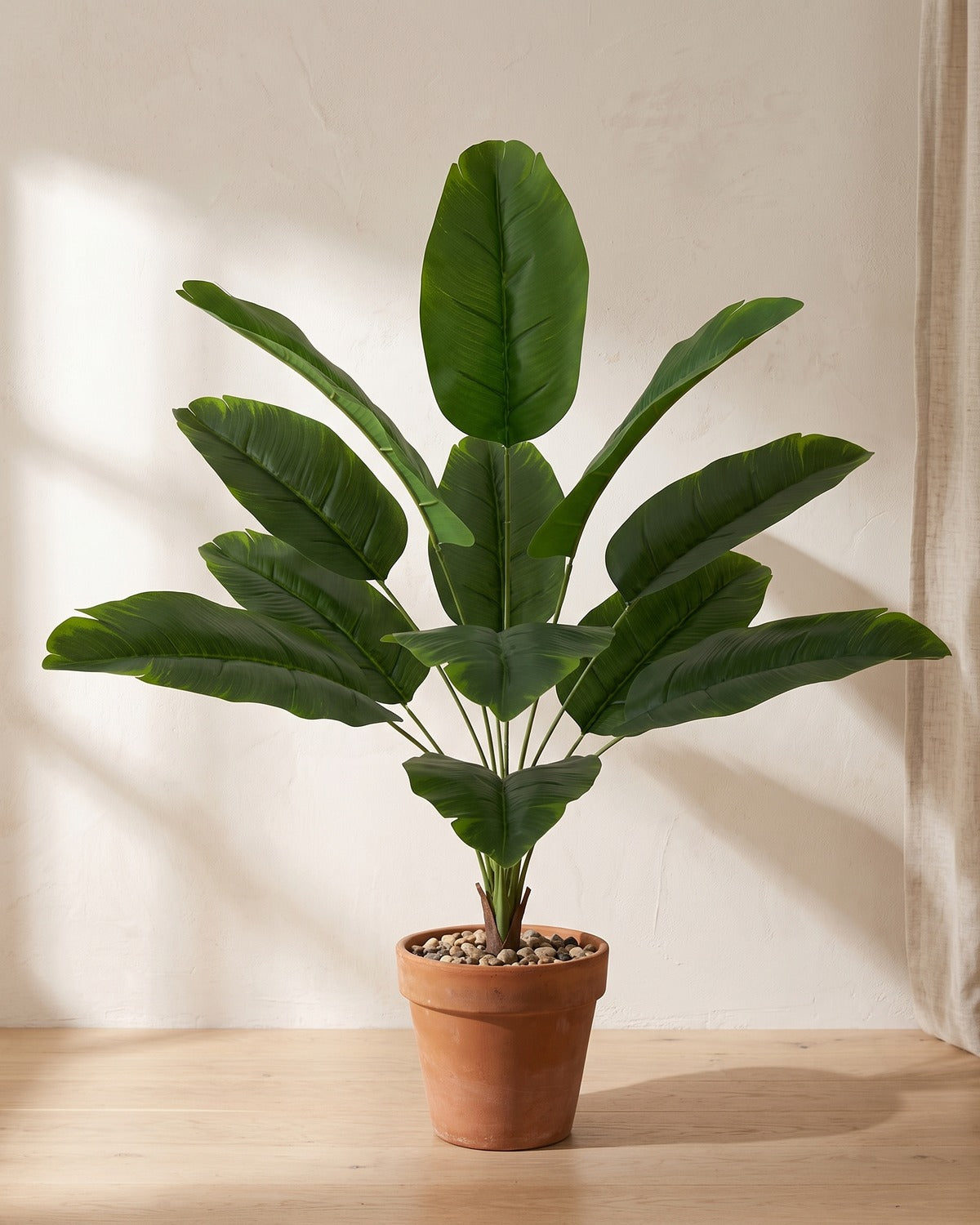 Artificial banana leaf bush, 25.6 in with twelve leaves, in a plain terracotta pot on pale oak floorboards; pot not included