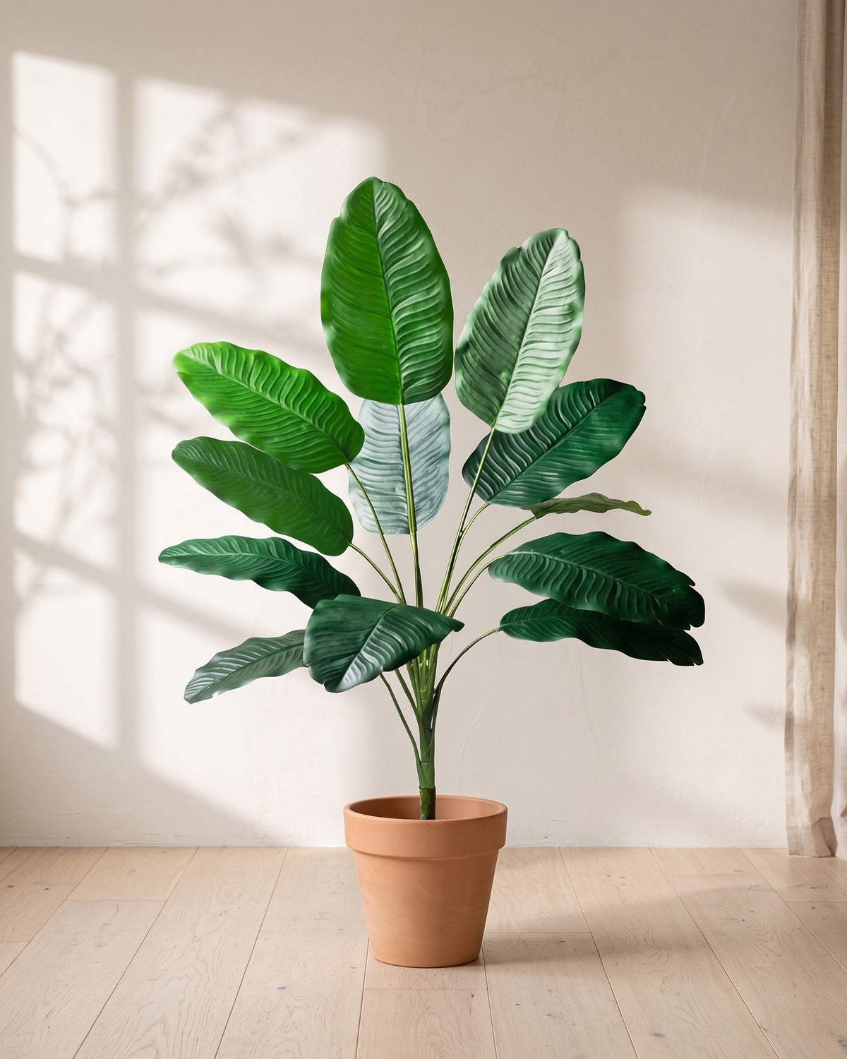 Green leaf artificial banana leaf plant, 33.9 in with twelve leaves, in a plain terracotta pot on pale oak floorboards; pot not included