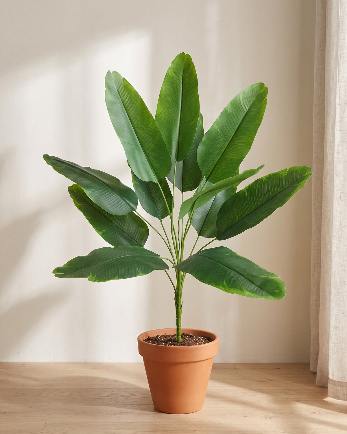 Green leaf artificial banana leaf plant, 34.6 in with twelve leaves, in a plain terracotta pot on pale oak floorboards; pot not included