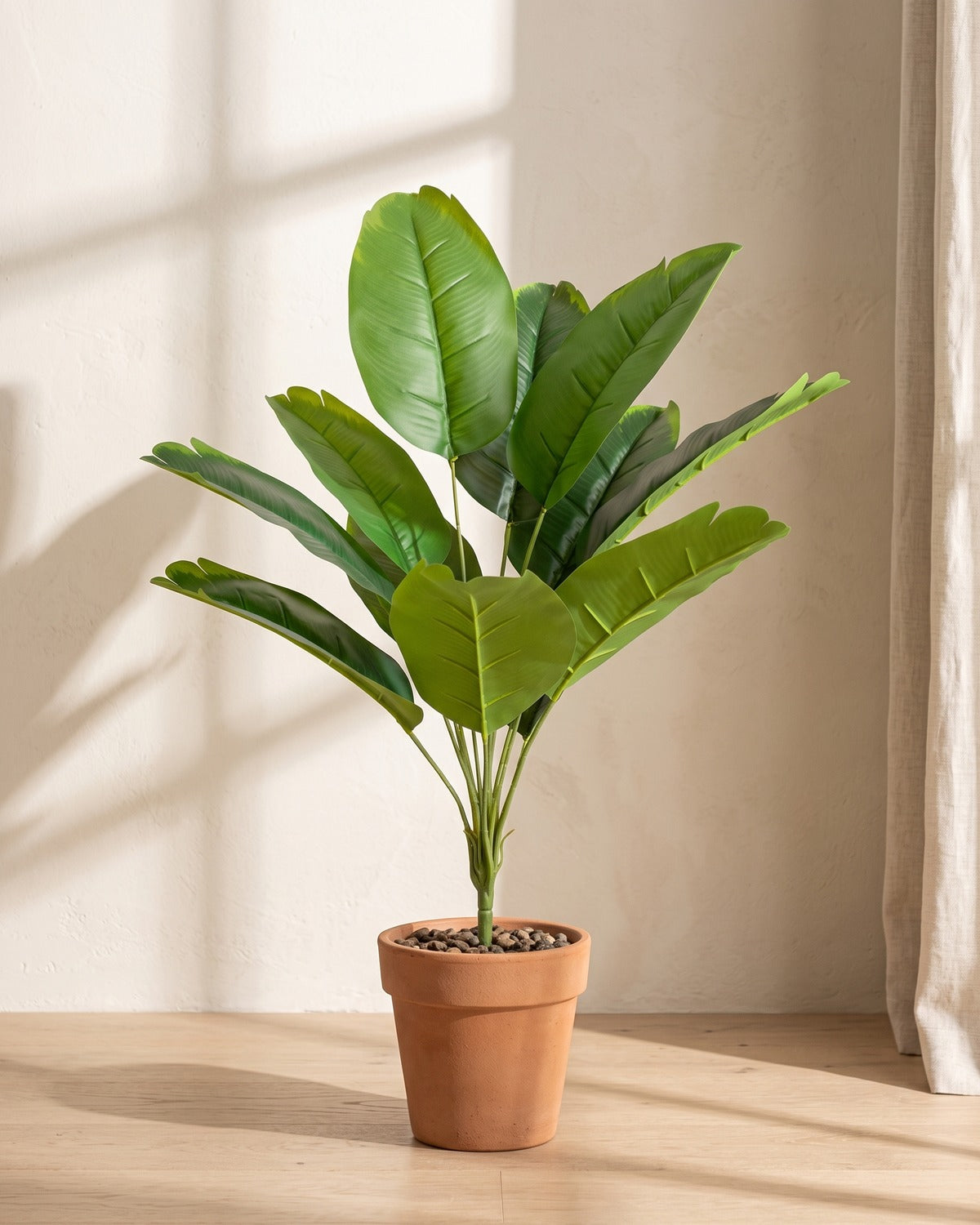 Green leaf artificial banana leaf plant, 26.6 in with twelve leaves, in a plain terracotta pot on pale oak floorboards; pot not included