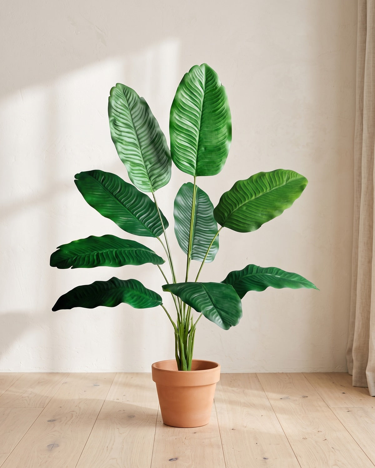 Green leaf artificial banana leaf plant, 34.6 in with nine leaves, in a plain terracotta pot on pale oak floorboards; pot not included