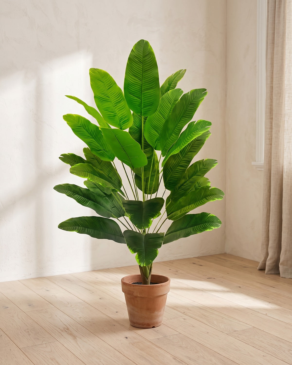 Green leaf artificial banana leaf plant, 47.2 in with twenty-four leaves, in a plain terracotta pot on pale oak floorboards; pot not included