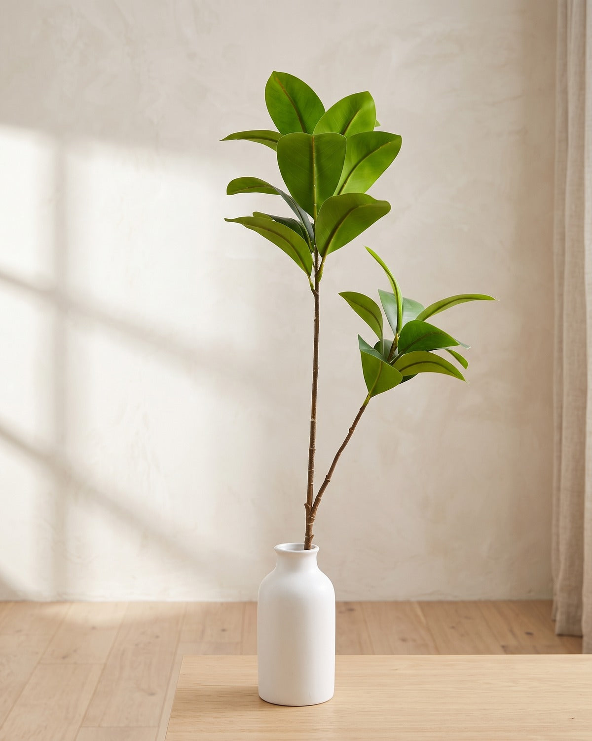 Glossy oval leaf artificial tree branch, 2 stems, 41.3 in, standing in a plain white vase on a pale oak table; no vase is included