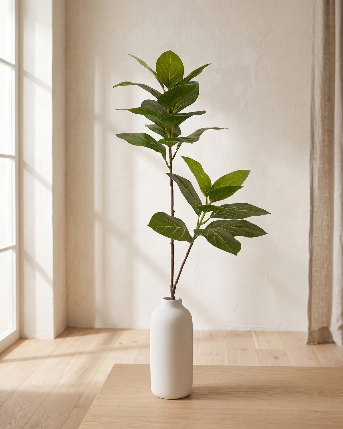 Veined oval leaf artificial tree branch, 2 stems, 41.3 in, standing in a plain white vase on a pale oak table; no vase is included