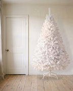A white artificial Christmas tree at 8 ft on its folding stand, beside an 80 in door to show its height
