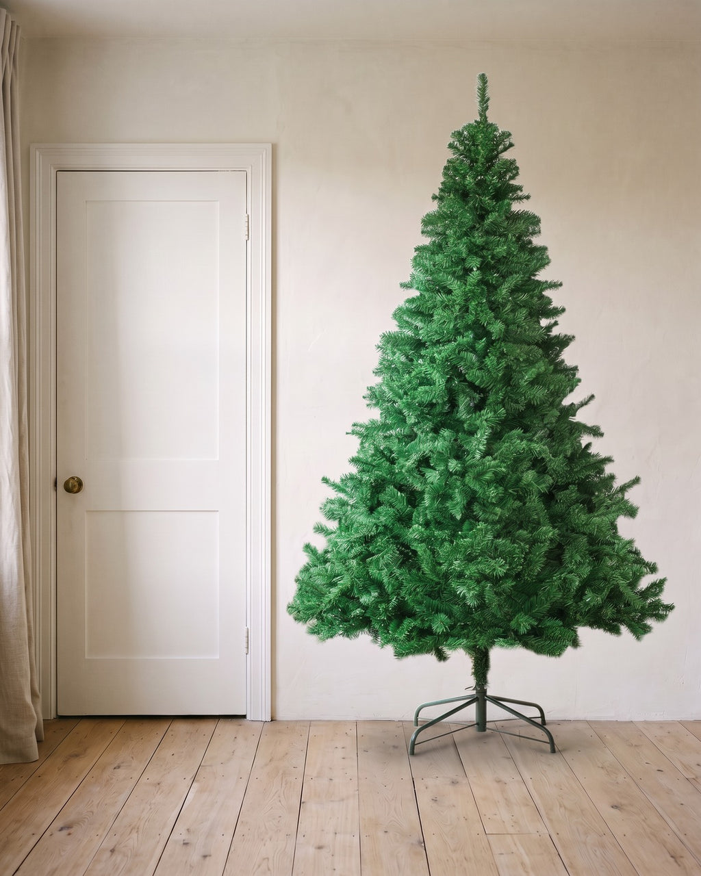 A green artificial spruce Christmas tree at 8 ft on its folding stand, beside an 80 in door to show its height